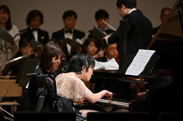 Kiwa Usami (centre), who has cerebral palsy, performs with one index finger, playing an AI-powered piano during a Christmas co<em></em>ncert of Beethoven's 'Symphony No 9' with the Yokohama Sinfo<em></em>nietta orchestra in Tokyo. Photo: AFP